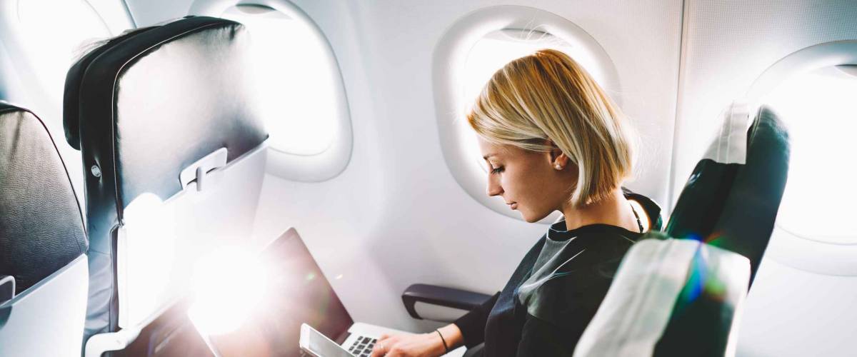 Woman checking incoming notification on smartphone sitting on seat of airplane