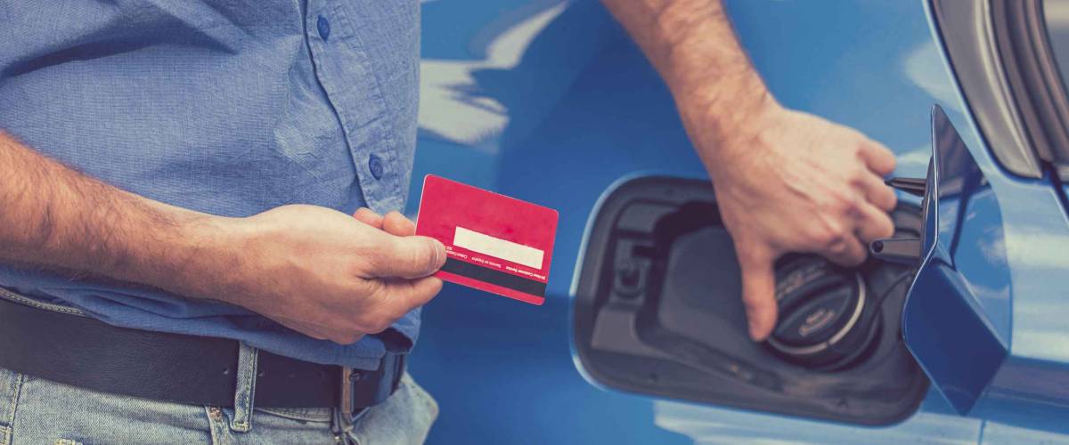 Man with credit card opening fuel tank of his new car