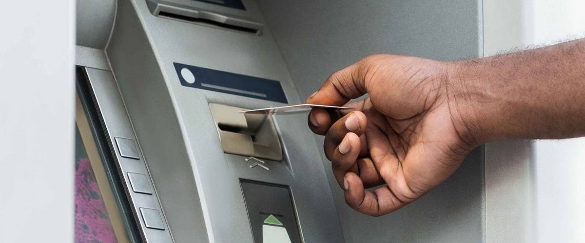 Unrecognizable african man putting credit card into ATM