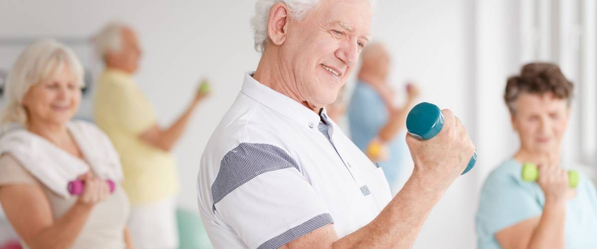 Older man in sportswear training together with his friends using dumbbells