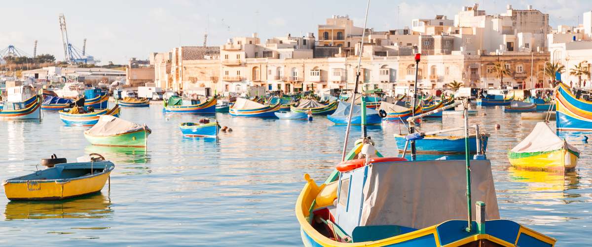 Mediterranean traditional colorful boats luzzu. Fisherman village in the south east of Malta. Early winter morning in Marsaxlokk, Malta.
