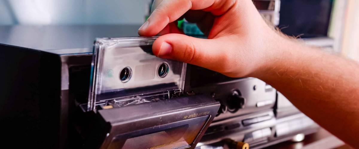 Close up man's hand put CD cassette into old fashioned cd audio player. Selective focus