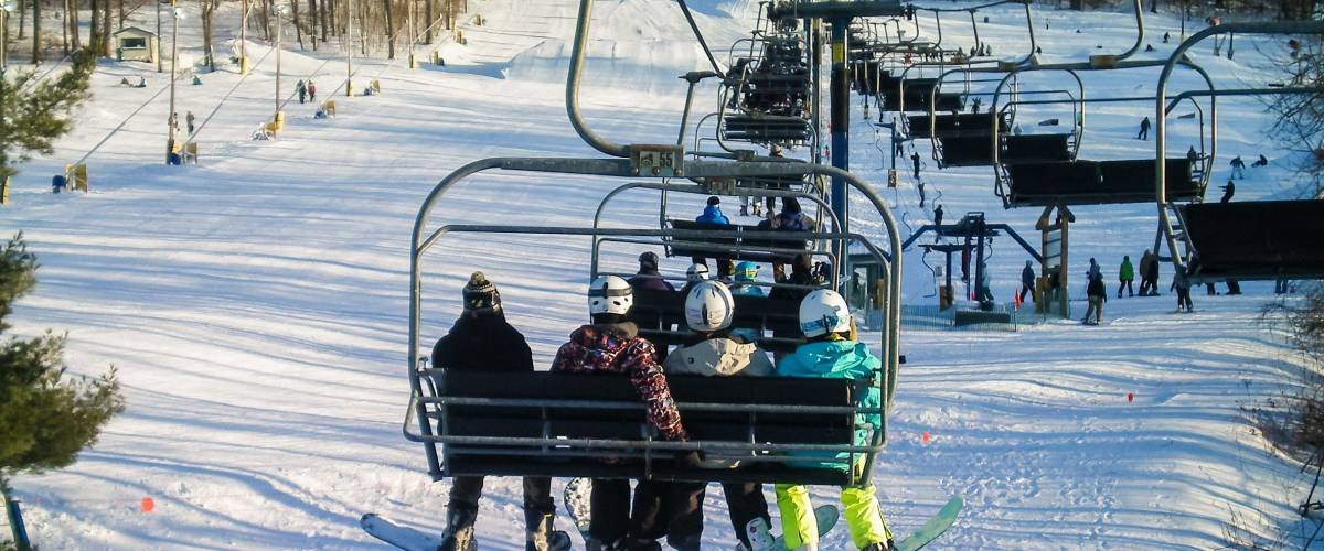 Snowshoe, USA - January 9, 2010: Mountain ski lift with people sitting with snowboards