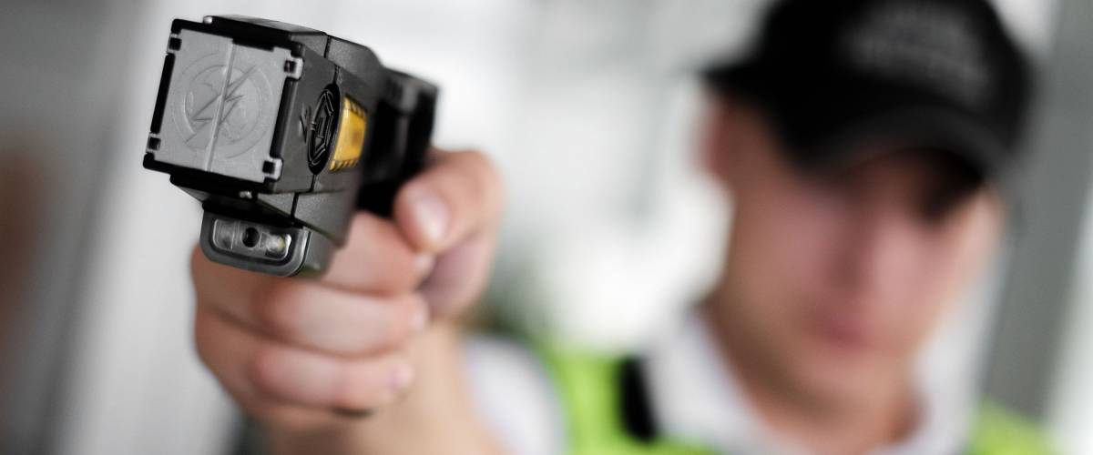 Closeup view of a loaded stun gun in a hand of a young man wearing high visibility vest