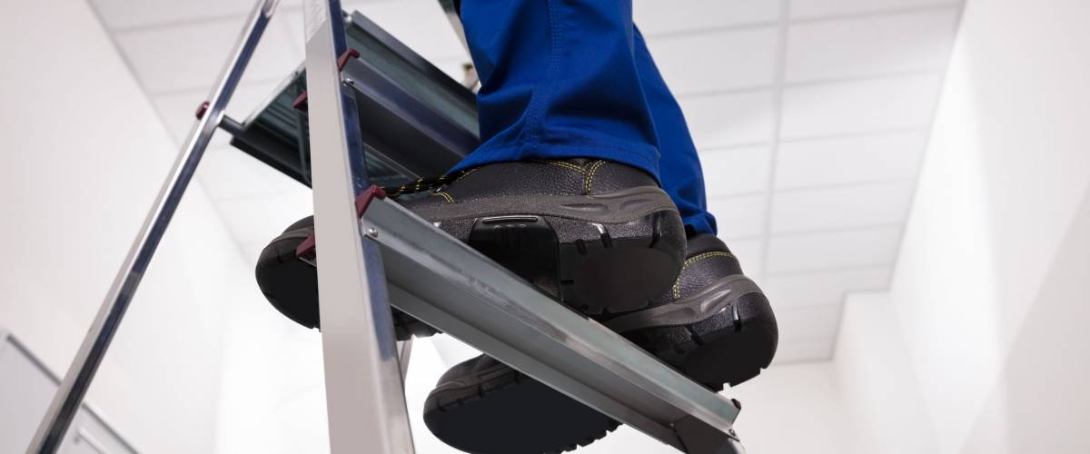 Close-up Of Man Standing On Steel Ladder