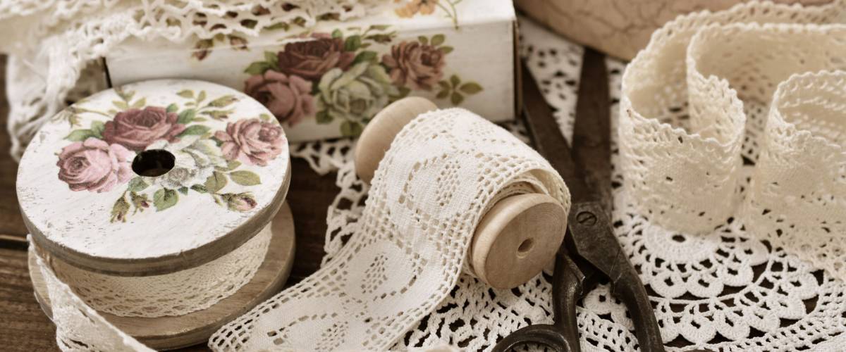 vintage cotton lace trims on wooden spools and sewing items lying on the table