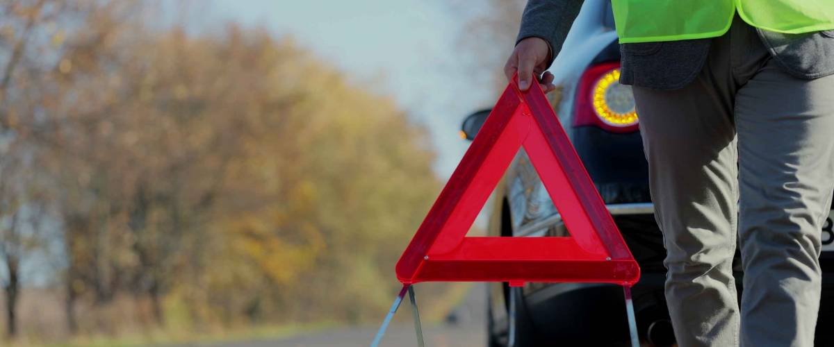 Close up of person carrying red warning sign near car parked on road