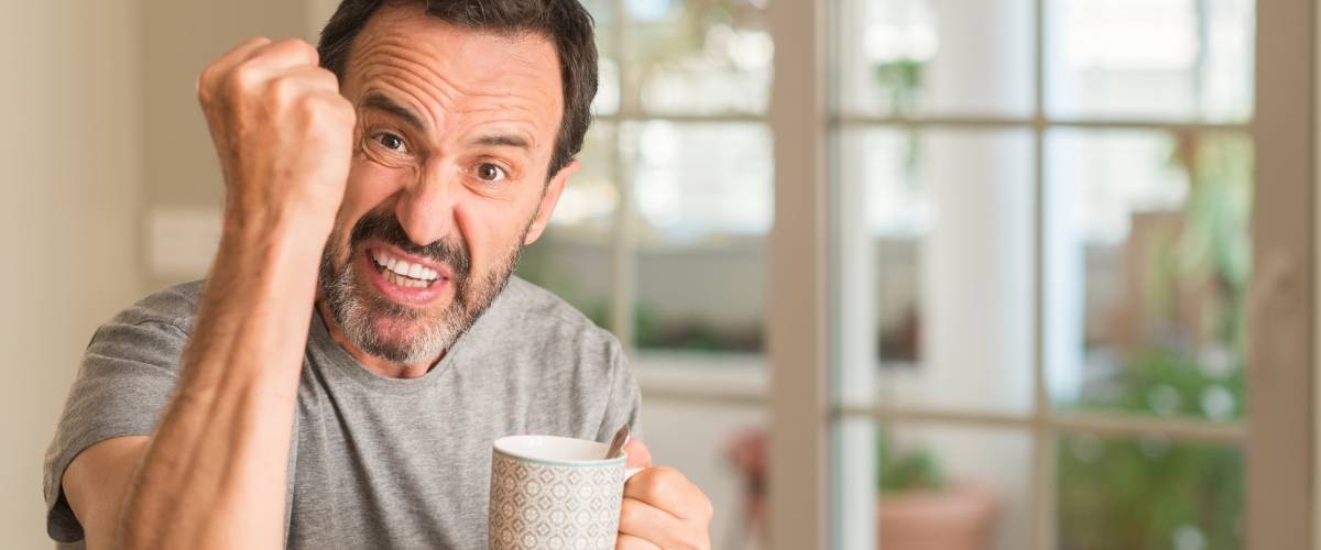 Man with coffee cup angrily shaking fist