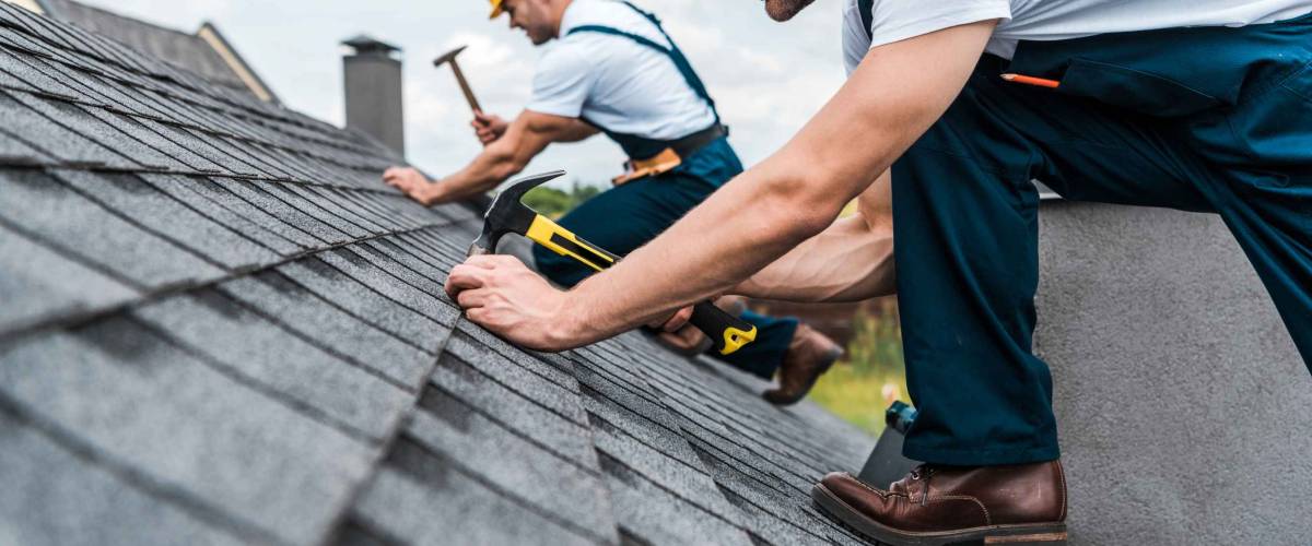 selective focus of handsome handyman repairing roof with coworker