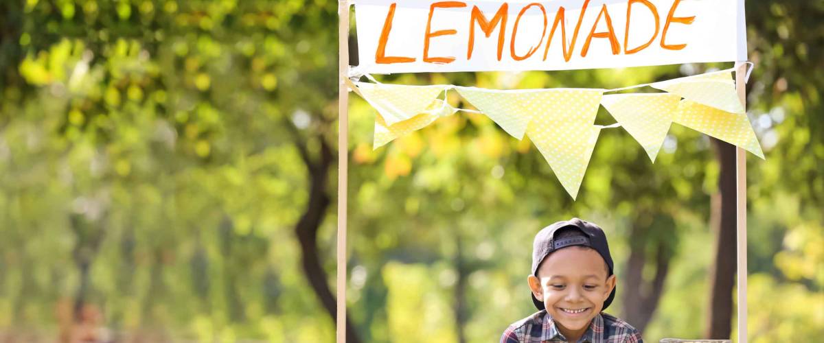 Little African-American boy at lemonade stand in park