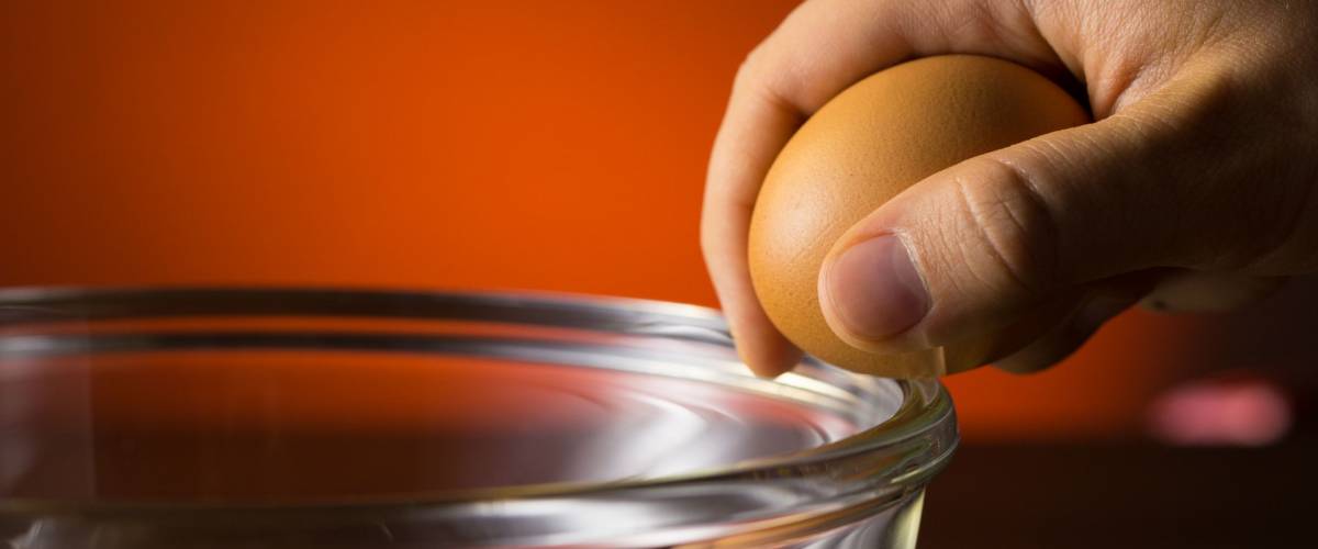 Man's Hand Cracking and pouring an Egg into a Bowl.