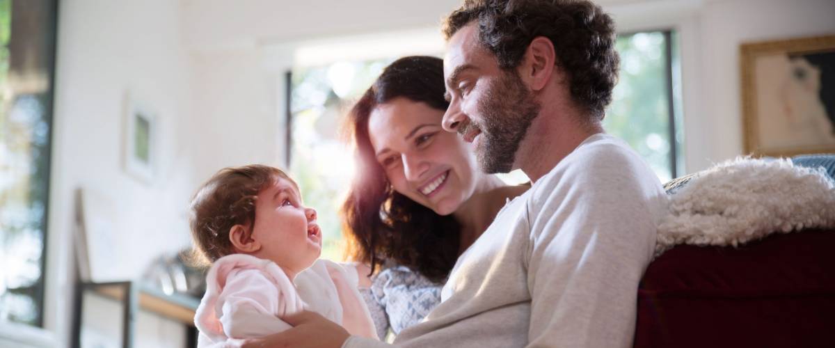 A beautiful couple with their baby sitting on the couch in the living room