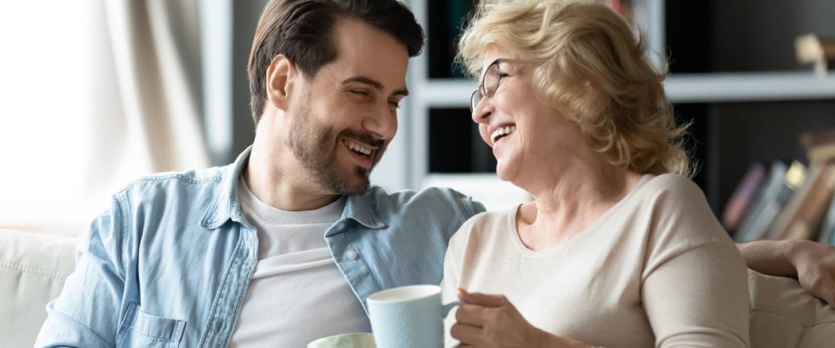 Older woman and young man laughing together on couch