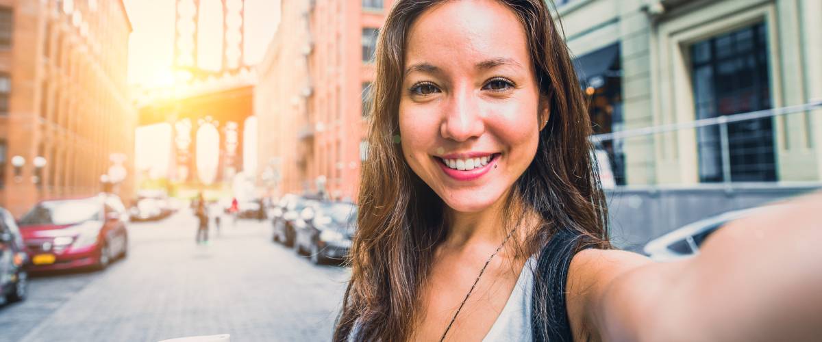 Woman taking a smiling selfie on city street