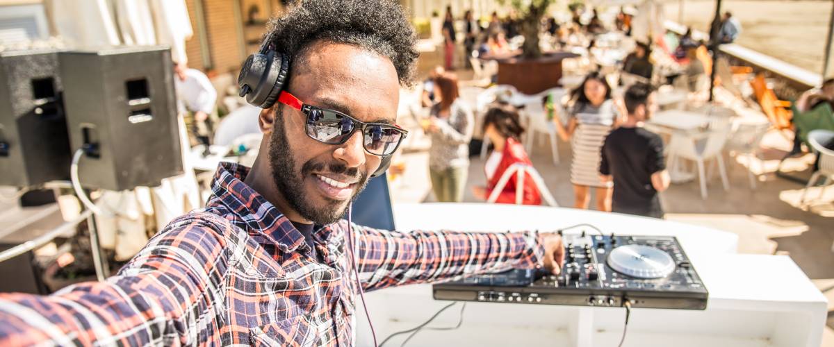 Man DJ-ing and taking a selfie with crowd