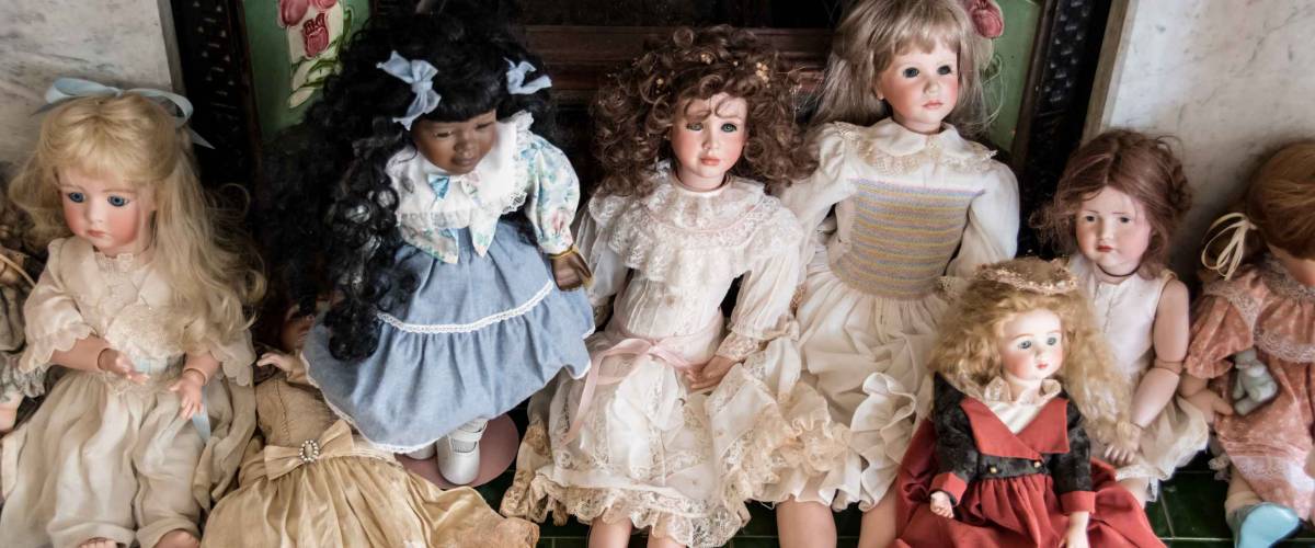 Antique porcelain doll collection laid out in front of old fireplace