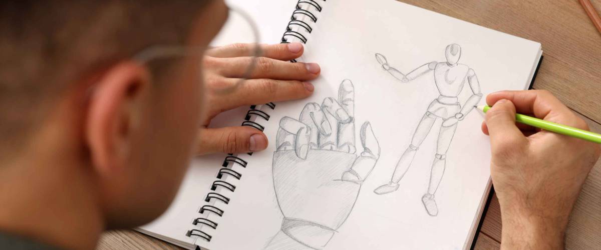 Man drawing in sketchbook with pencil at wooden table, closeup