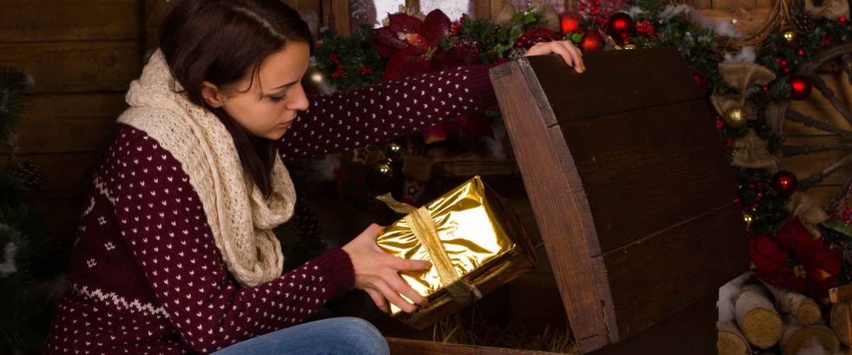 Sitting Young Woman getting Christmas Presents from a Vintage Wooden Trunk