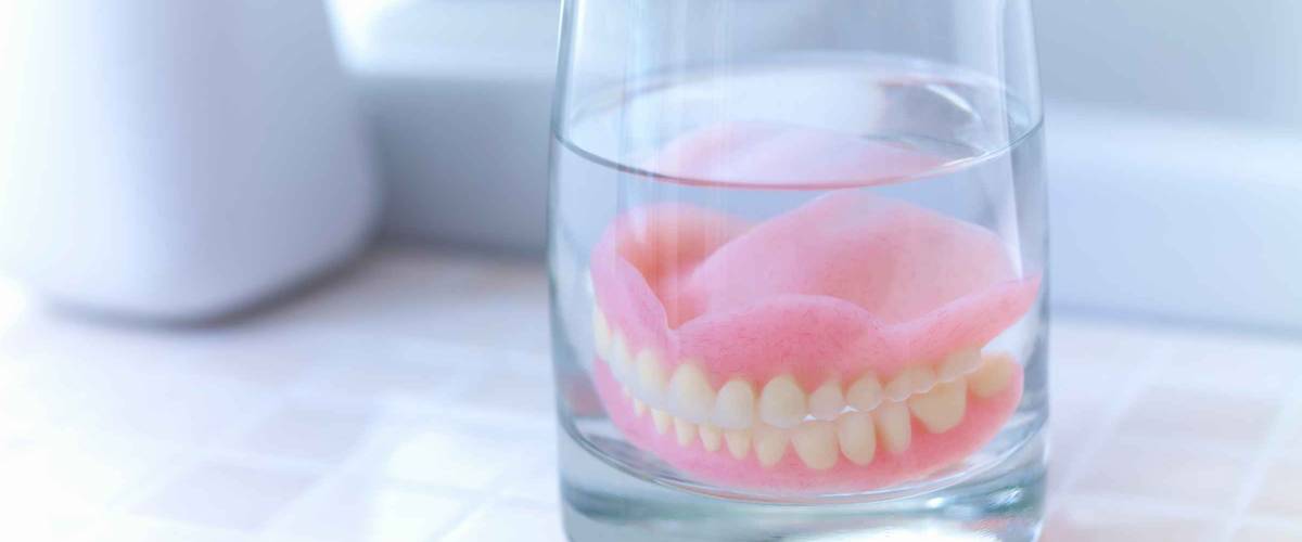 Close up of dentures soaking in glass of water