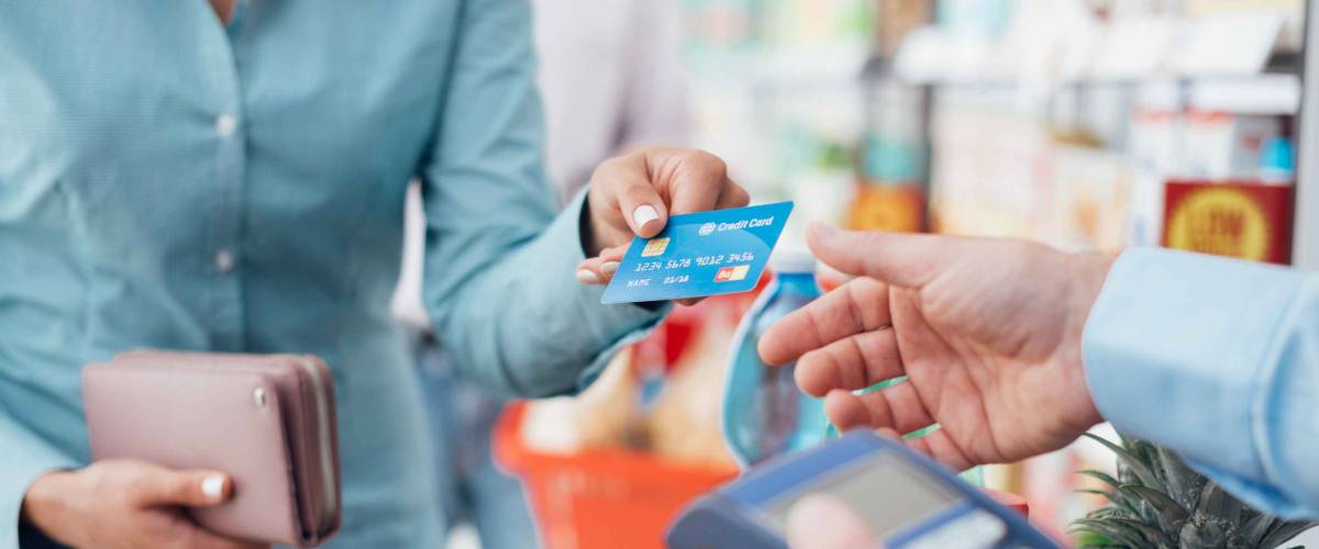 Woman at the supermarket checkout, she is paying using a credit card