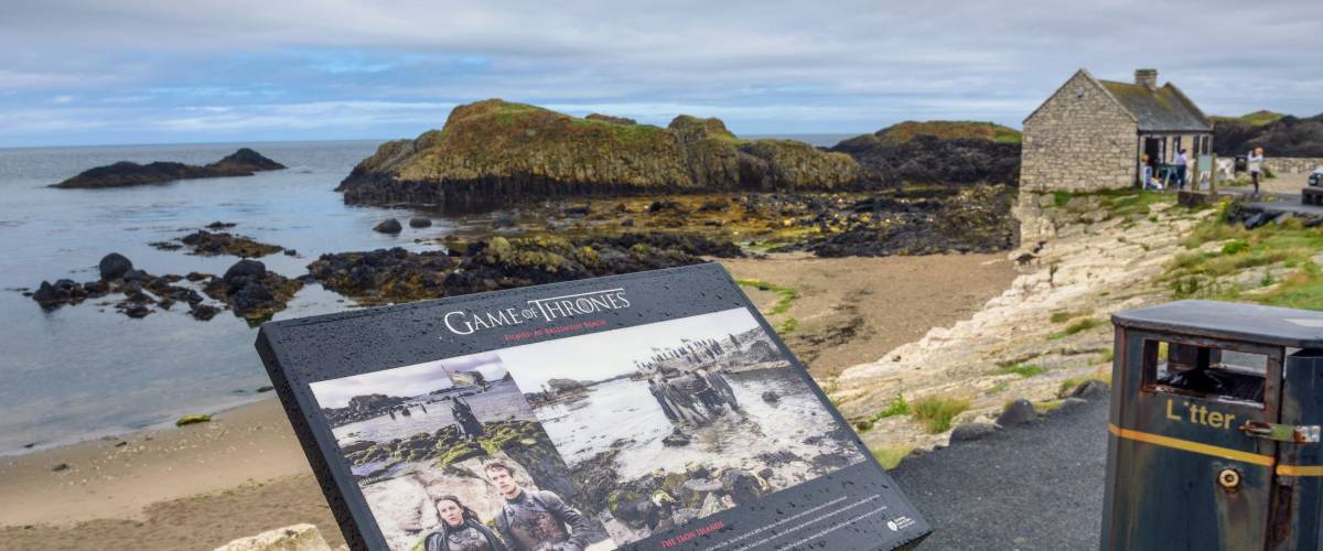 Ballintoy, UK - August 6, 2018 : Visitor information sign with Ballintoy harbor in the background