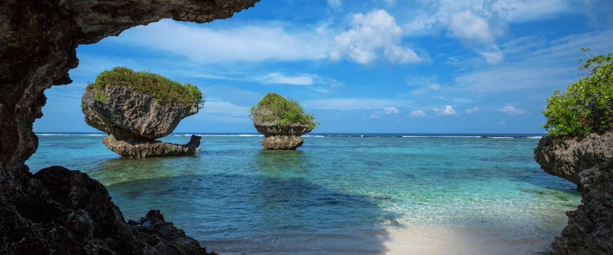 Beautiful rock formations along the sandy beach of Tanguisson Beach on the tropical island of Guam during the morning calm of the ocean on a clear, sunny day