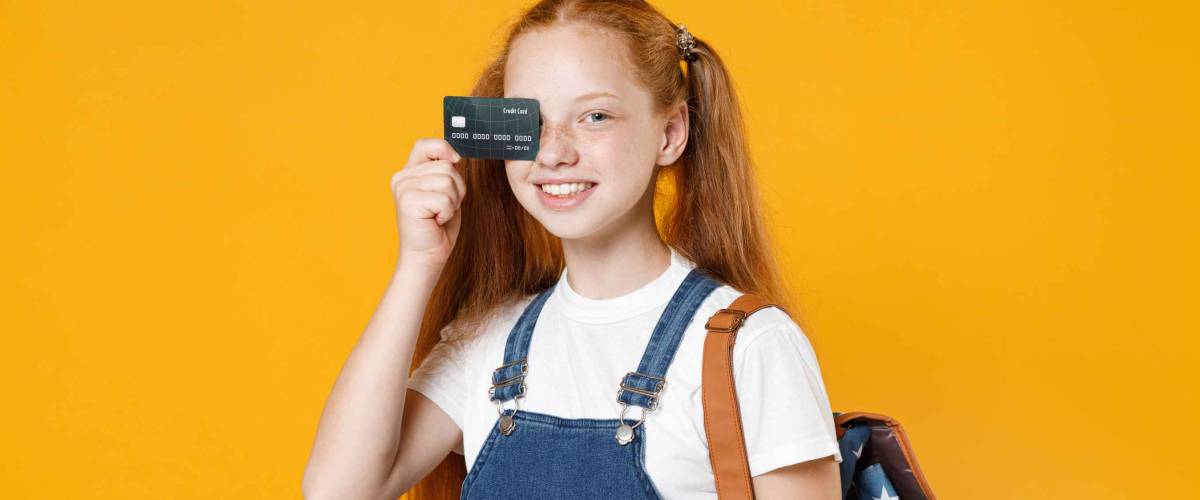 Young redhead school teen with debit card over eye
