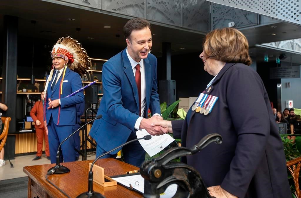 The Manitoba government is planning to do away with paper health cards and switch to more durable plastic and digital ones. Manitoba Premier Wab Kinew looks on as Finance Minister Adrien Sala