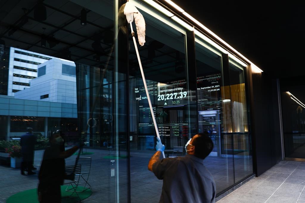 A signboard displays the TSX as a custodian cleans the windows of the Richmond Adelaide Centre in the financial district in Toronto on Wednesday, September 29, 2021. 