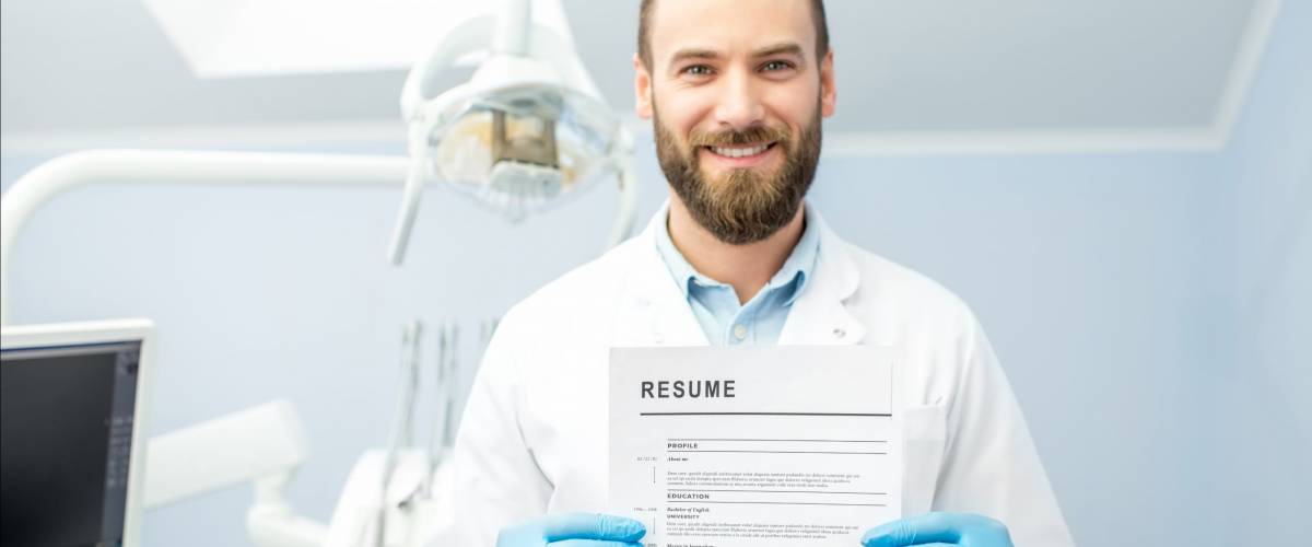 Professional dentist holding resume for a new job standing at the dental office
