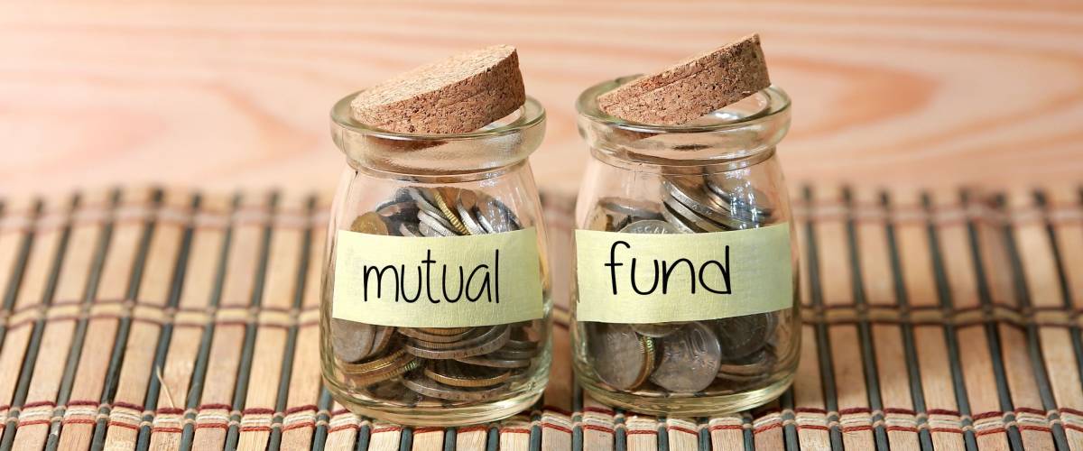 Coins in jar. Writing Mutual Fund on two jar with wooden pallet background. Selective focus with shallow depth of field.