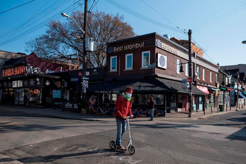 A new report lays out how an innovative funding model for community groups could be scaled up. A man scooters down an empty Kensington Market in Toronto, Wednesday, April 7, 2021. 
