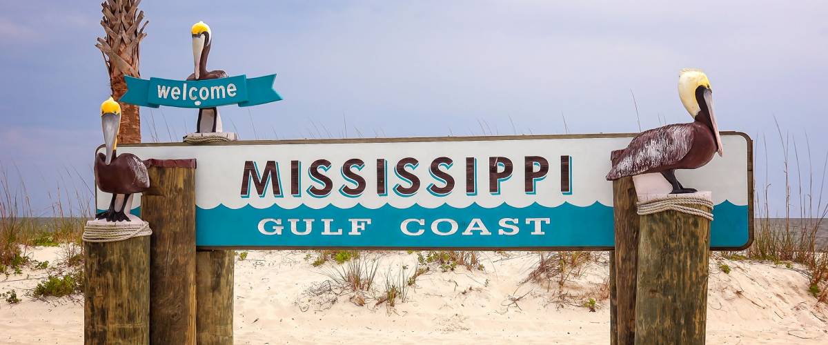 Welcome to Mississippi Gulf Coast sign on sandy beach in Gulfport