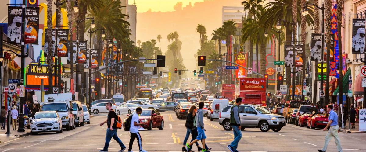 LOS ANGELES, CALIFORNIA - MARCH 1, 2016: Traffic and pedestrians on Hollywood Boulevard at dusk. The theater district is famous tourist attraction.