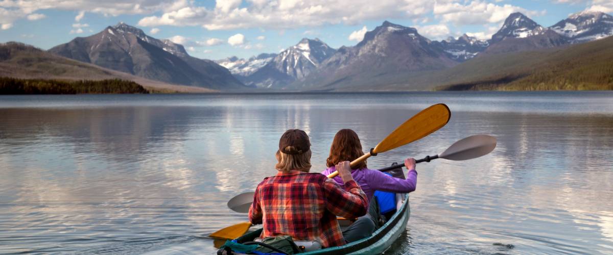 Adventurous traveling couple rowing a boat on a perfect scenic lake in a beautiful national park