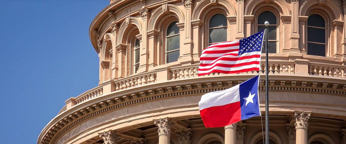 American and Texas state flags flying on the dome of the Texas State Capitol building in Austin