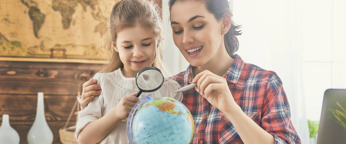 mom and young daughter look at globe