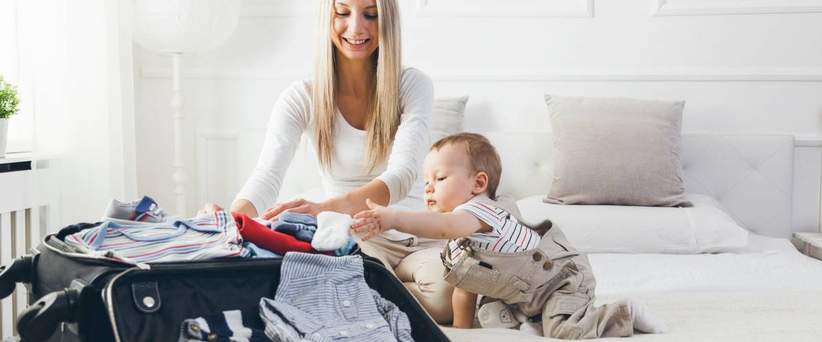 Mom packing suit case with baby son to her right