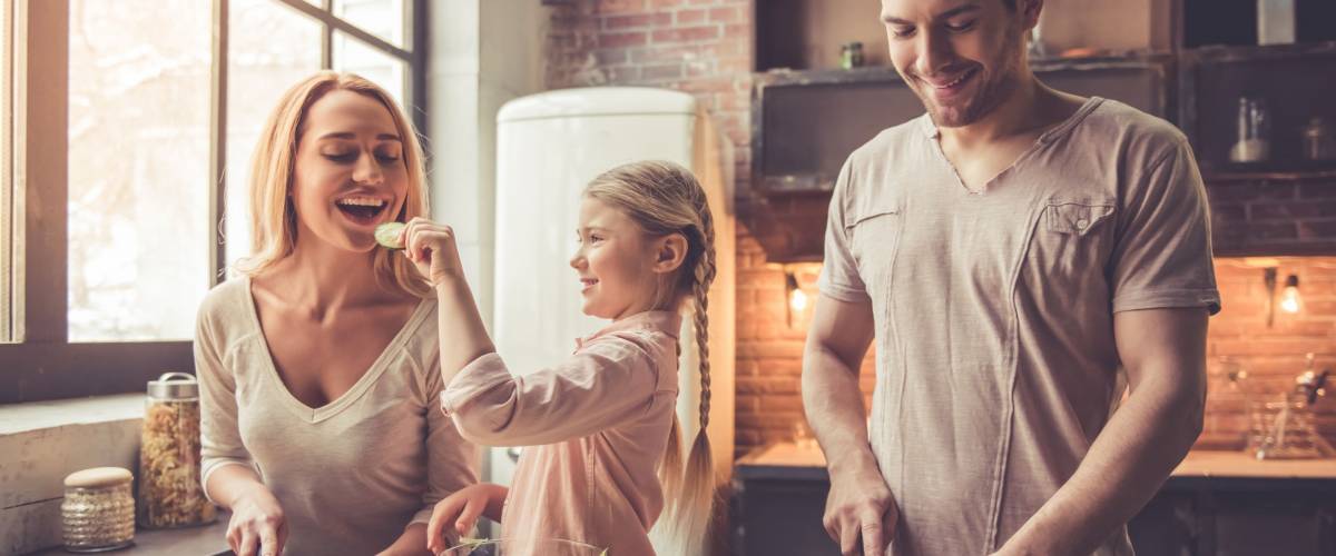 a little girl and her parents are chopping vegetables