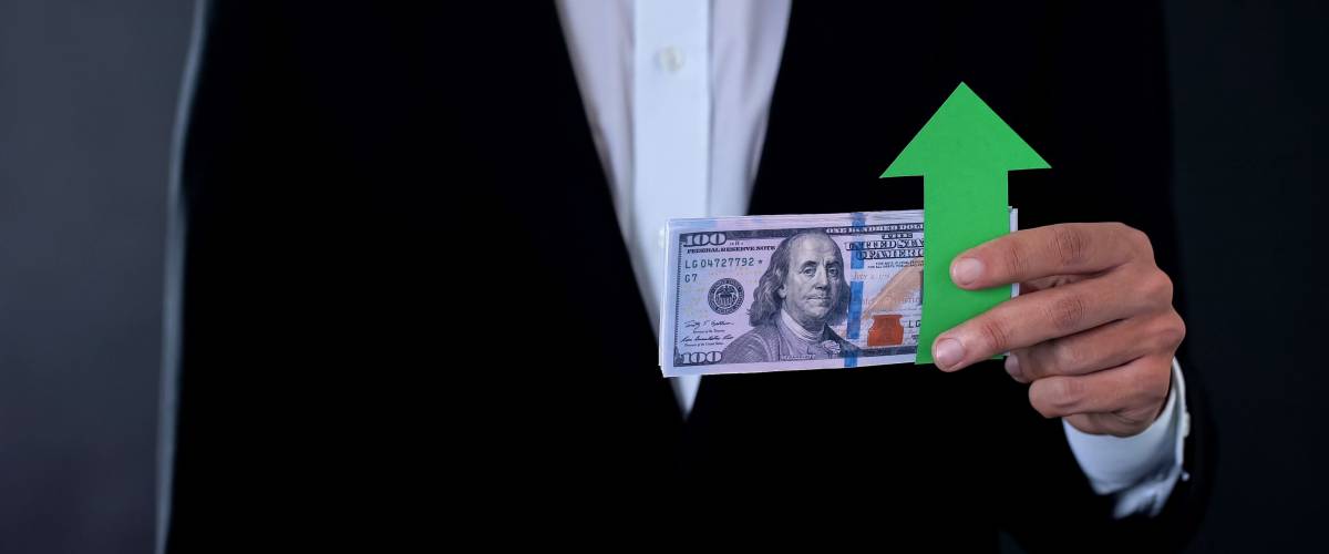 man holding banknote, arrow pointing up indicating strong dollar and strong US economy