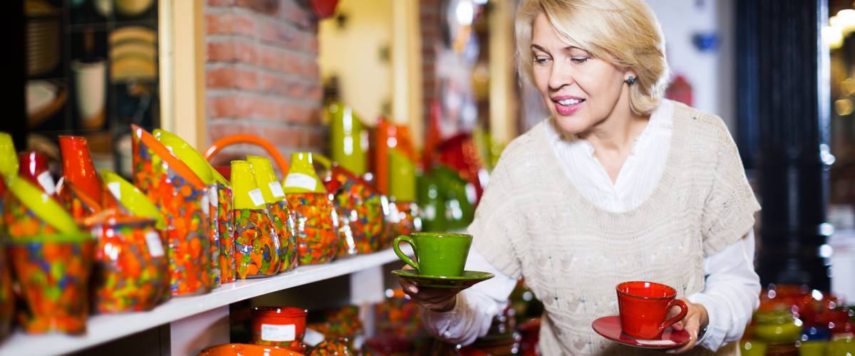 Blonde woman chooses ceramic ware in the cookware section at hypermarket