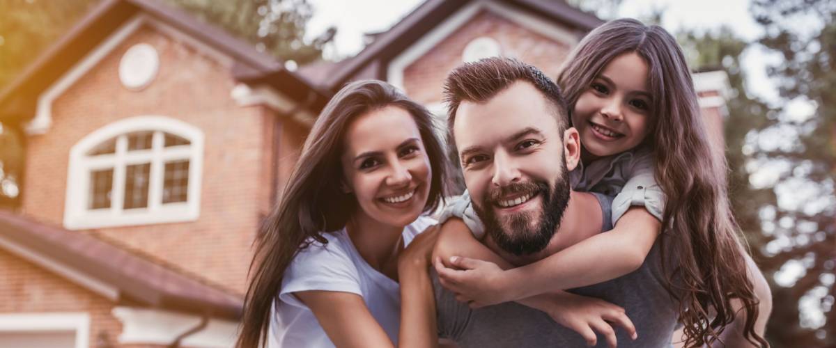 Happy family is standing in front of their home.