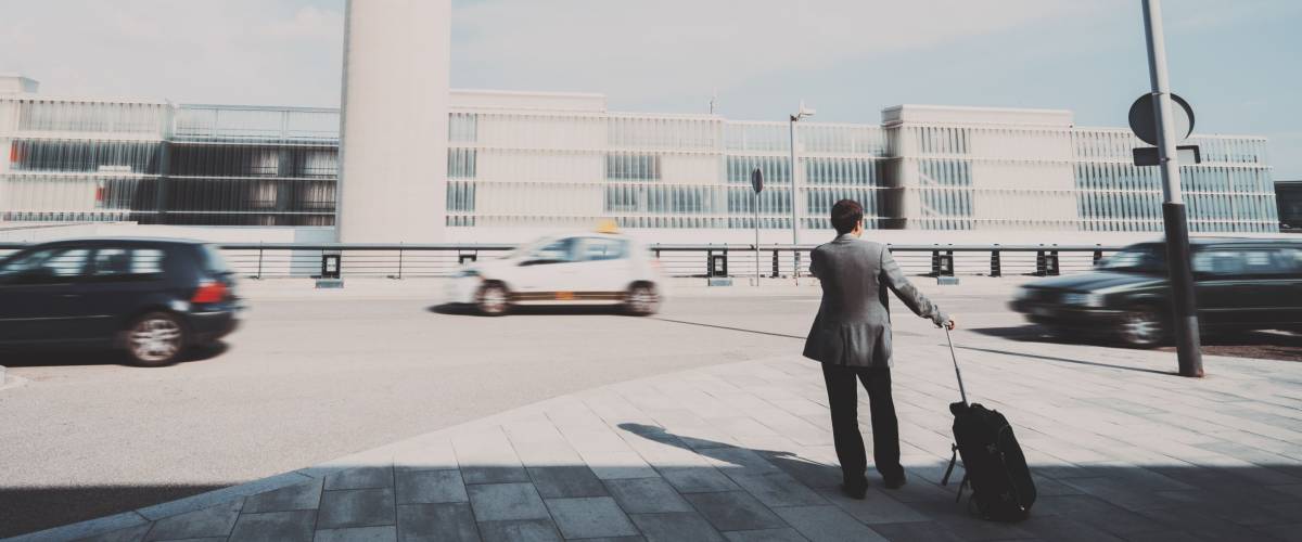 man with luggage in an airport parking lot