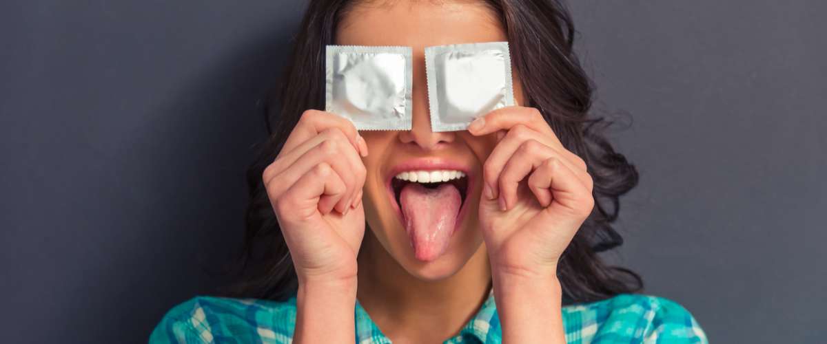 Portrait of girl covering eyes with condoms