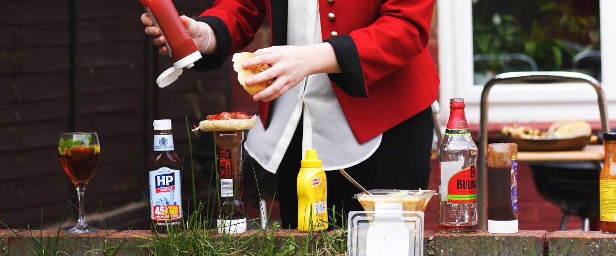 woman in red jacket dressing food with ketchup