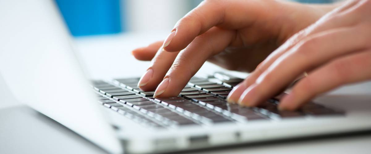 woman's hands typing on laptop