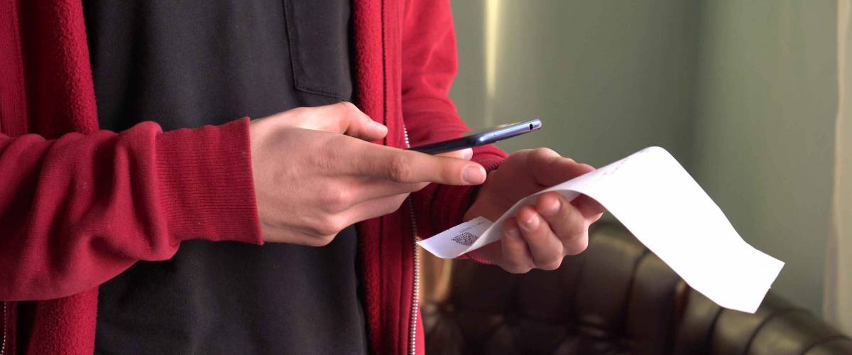 A man scans the QR code on a check from a supermarket