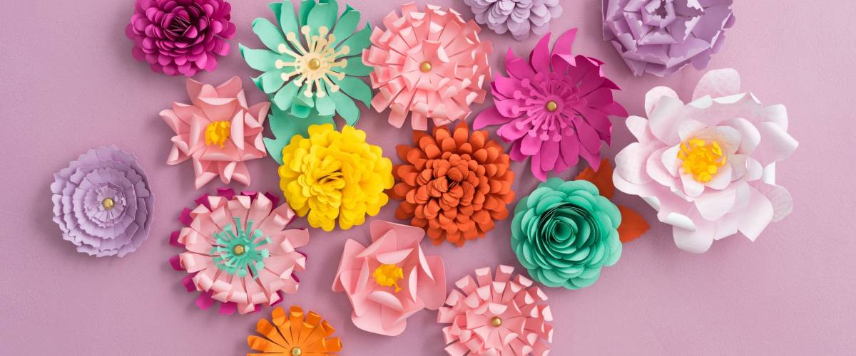 Colourful handmade paper flowers on pink background