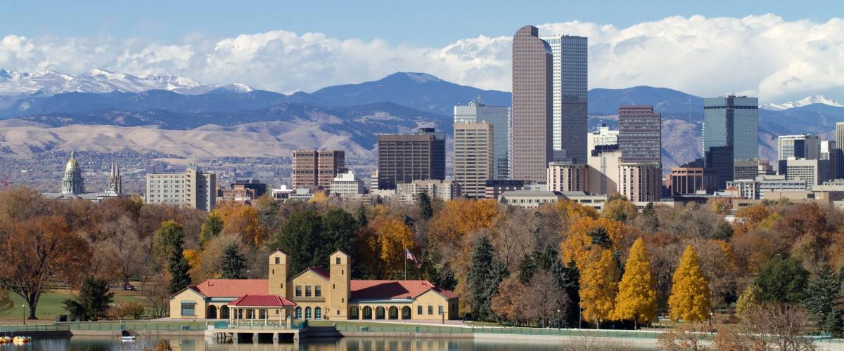 Scenic of Denver Colorado skyline, with Rocky Mountains in the background and City Park Lake in the foreground.