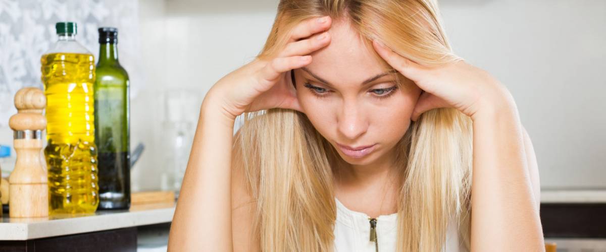 Young sad blonde housewife filling in utility payments bills at home
